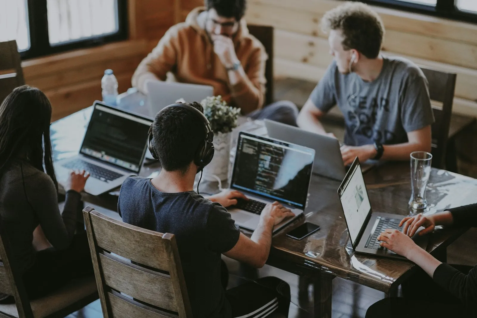 A small team working together at a shared table, laptops open